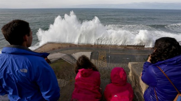 Una familia observa como una ola rompe contra el Paseo Nuevo de San Sebastián Efe