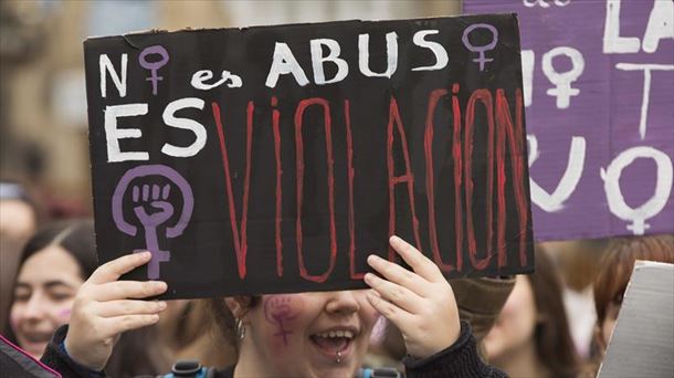 Una mujer sostiene un cartel que dice "no es abuso, es violación". 