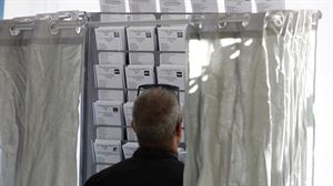 Un hombre frente a las papeletas de voto