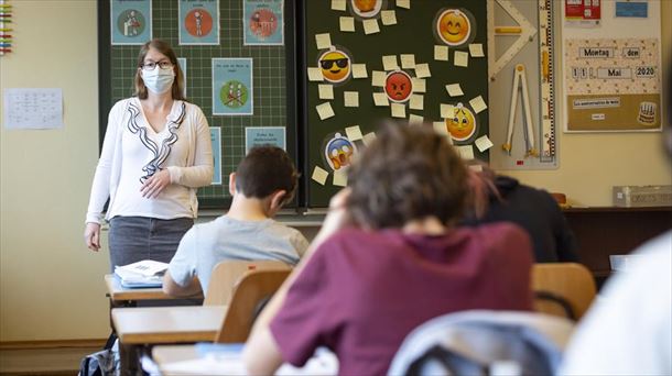 Una maestra con mascarilla protectora con sus alumnos en una escuela.