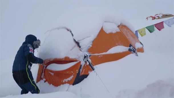 Un integrante de la expedición trata de limpiar de nieve una tienda