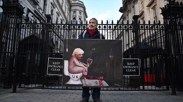 El artista Kaya Mar posa con una de sus obras frente a Downing Street. Foto: EFE